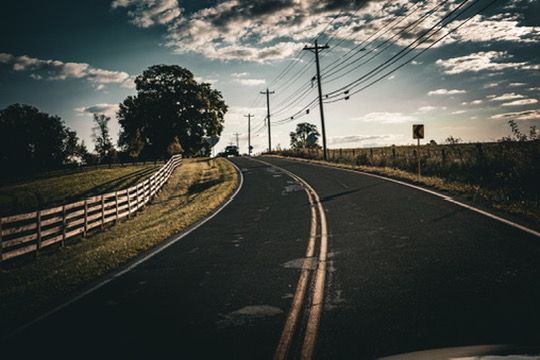 A two-lane Kentucky road curving past a plank fence