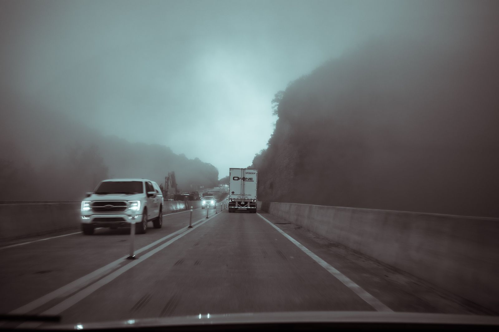 Interstate traffic in heavy fog through a hillside cut